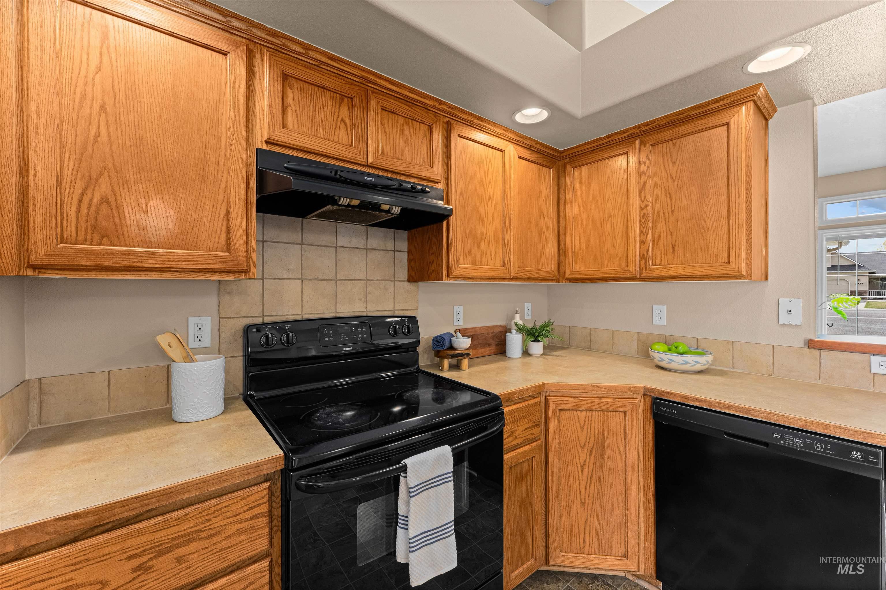 3923 Chatham Court Caldwell, ID 83607 - Photo 12 of 32 Kitchen featuring black appliances, light countertops, wood finish cabinetry, and tasteful backsplash