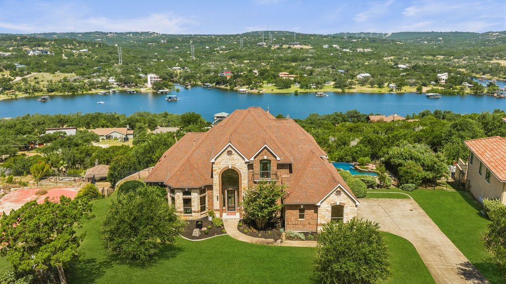 2702 Lakehurst Road Spicewood, TX 78669 - Photo 1 of 40 Stone and brick facade creates a grand entrance with a welcoming arched entryway and elegant landscaping.