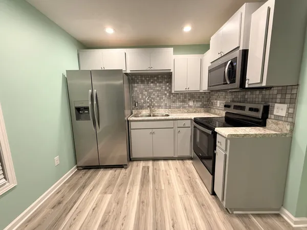 a kitchen with a sink a microwave a refrigerator and cabinets