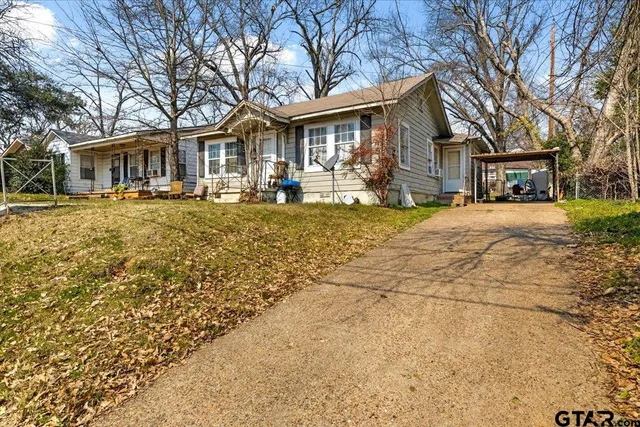 a front view of a house with a yard covered with trees