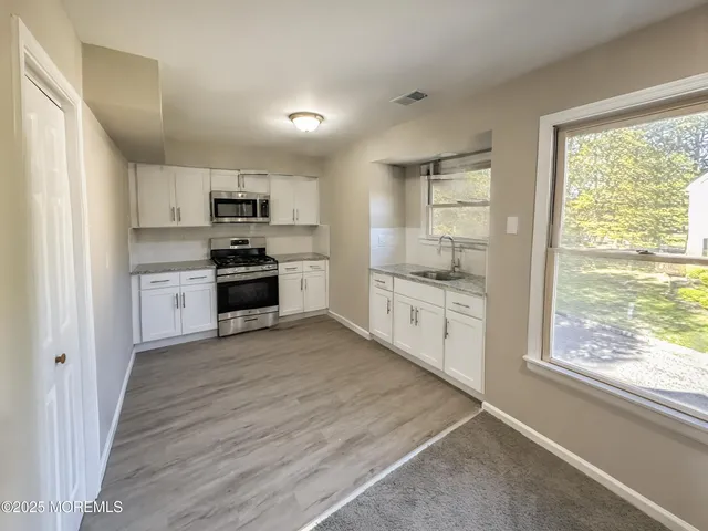 a kitchen with stainless steel appliances granite countertop a refrigerator a stove top oven a sink dishwasher and wooden floor