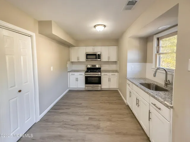 a kitchen with granite countertop white cabinets and white appliances