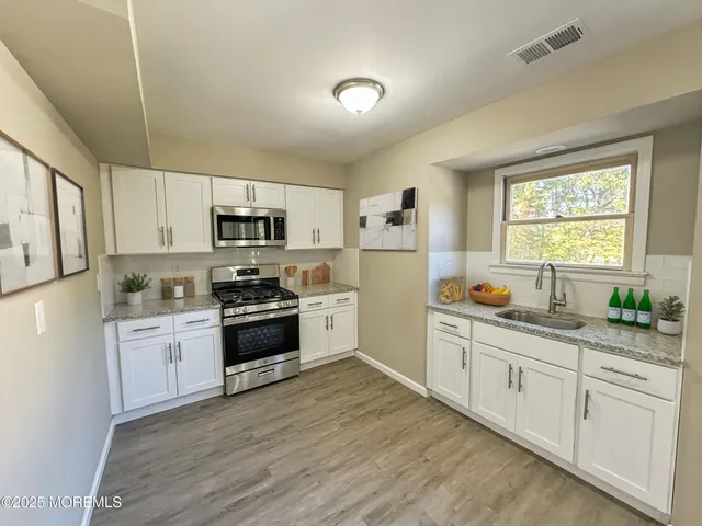 a kitchen with granite countertop white cabinets and stainless steel appliances