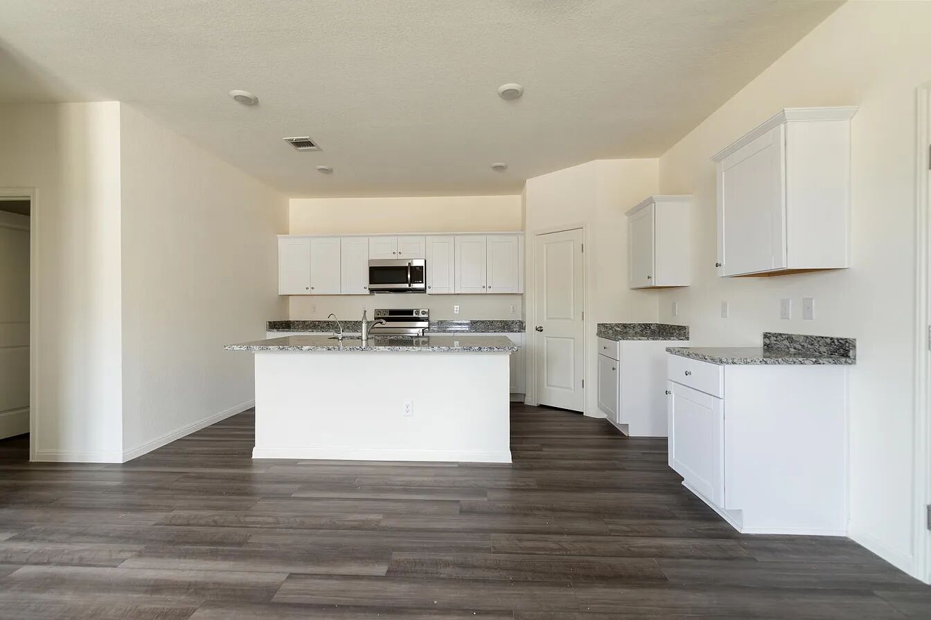 101 Aoudad Road Hutto, TX 78634 - Photo 3 of 39 An open-concept kitchen with white cabinetry and dark granite countertops awaits culinary adventures.