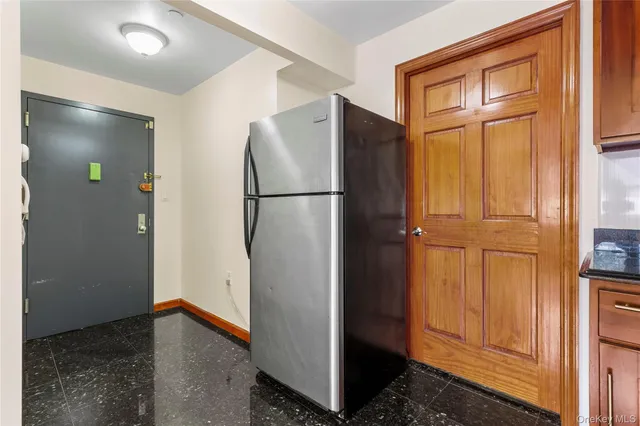 a view of a refrigerator in kitchen and wooden cabinets