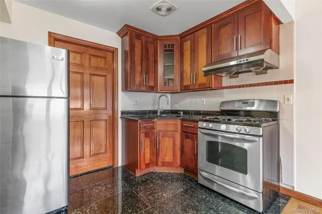 a kitchen with stainless steel appliances granite countertop a refrigerator a stove a sink and a microwave