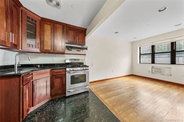 a kitchen with granite countertop a stove a sink and a microwave