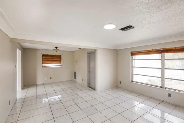 a view of an empty room with window and chandelier fan