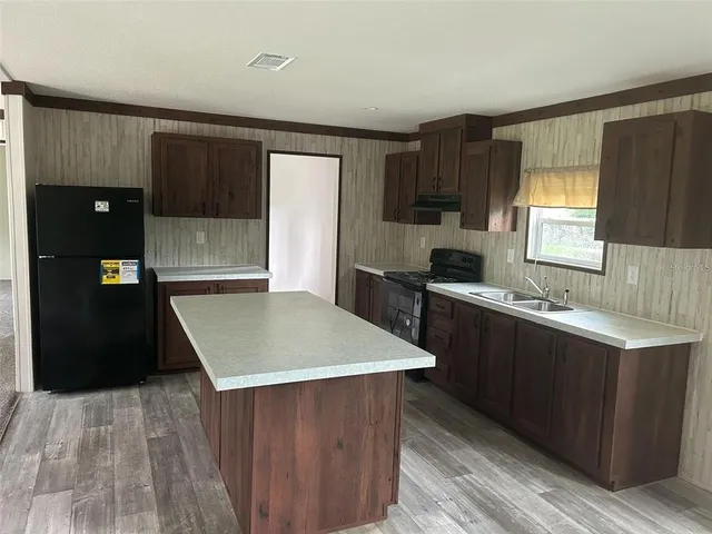 a kitchen with a wooden floor and black cabinets