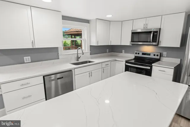 a open dining room with stainless steel appliances a dining table wooden floor windows and a kitchen view