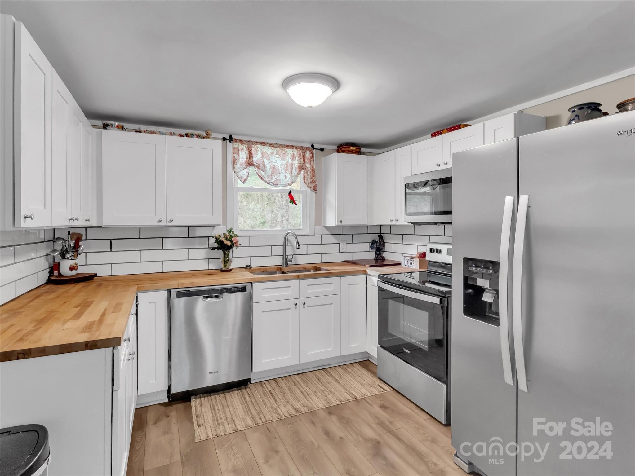 197 Mulberry Street Clyde, NC 28721 - Photo 12 of 20 a kitchen with stainless steel appliances granite countertop a refrigerator a sink dishwasher a stove and white countertops with wooden floor