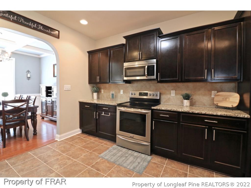 740 Sun Road Aberdeen, NC 28315 - Photo 11 of 36 a kitchen with stainless steel appliances granite countertop a stove a sink and a microwave