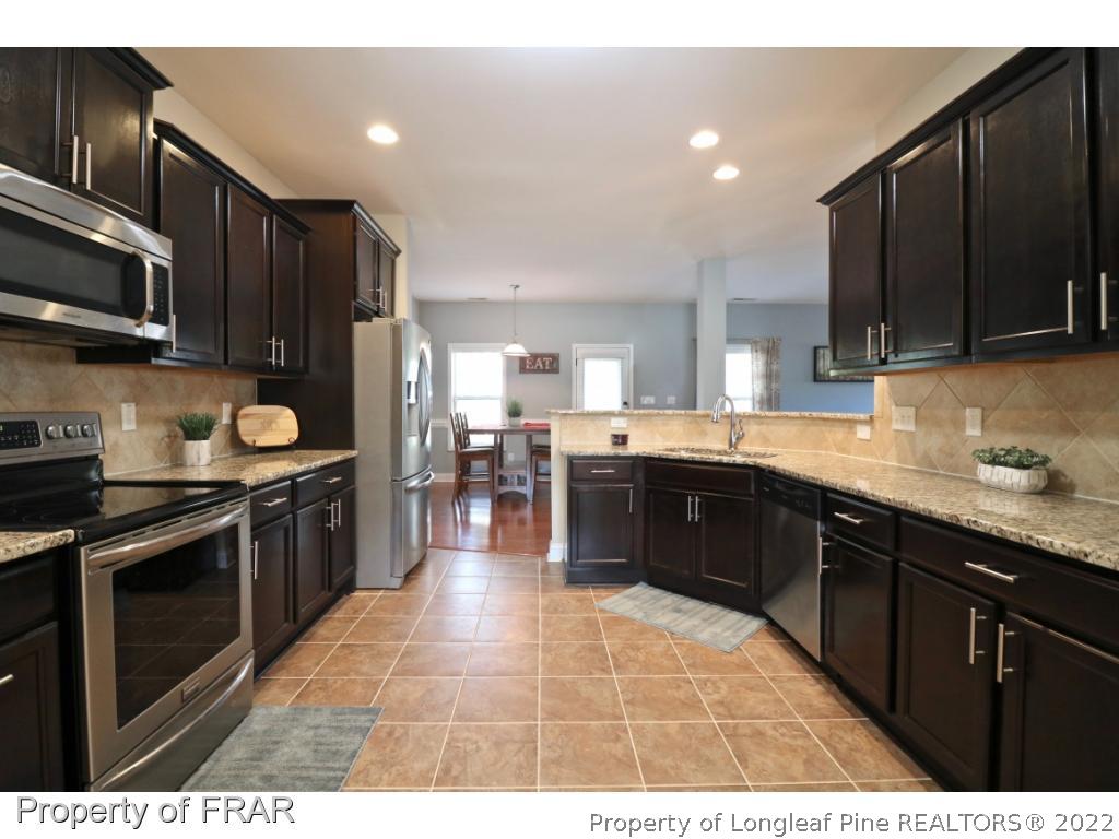 740 Sun Road Aberdeen, NC 28315 - Photo 13 of 36 a large kitchen with stainless steel appliances wooden cabinets and a stove top oven