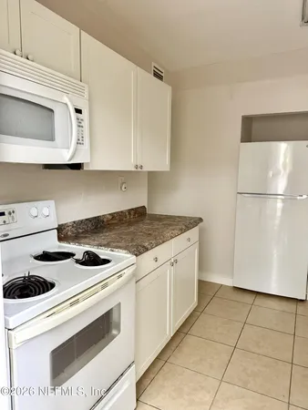 a kitchen with white cabinets and white appliances