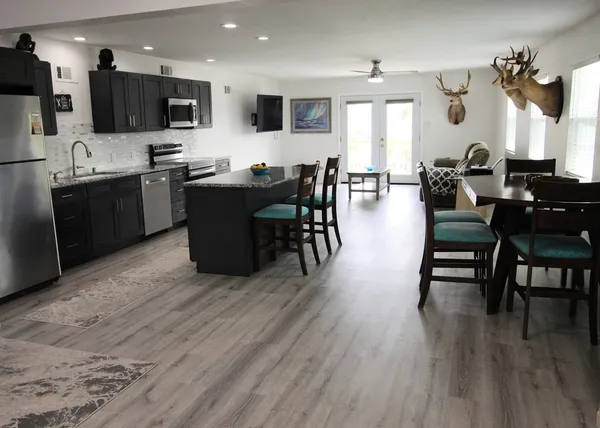 a living room with stainless steel appliances kitchen island granite countertop a refrigerator and cabinets
