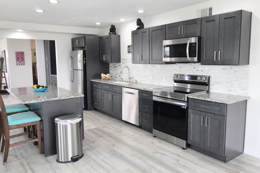 189 Sailfish Drive Rockport, TX 78382 - Photo 17 of 40 a kitchen with stainless steel appliances kitchen island granite countertop a stove a sink and a microwave