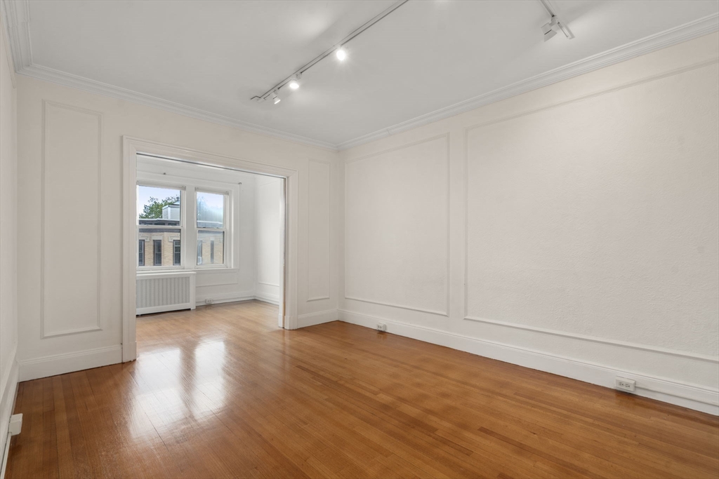 114 St Paul Street, Unit 5 Brookline, MA 02446 - Photo 4 of 22 a view of an empty room with wooden floor and a window