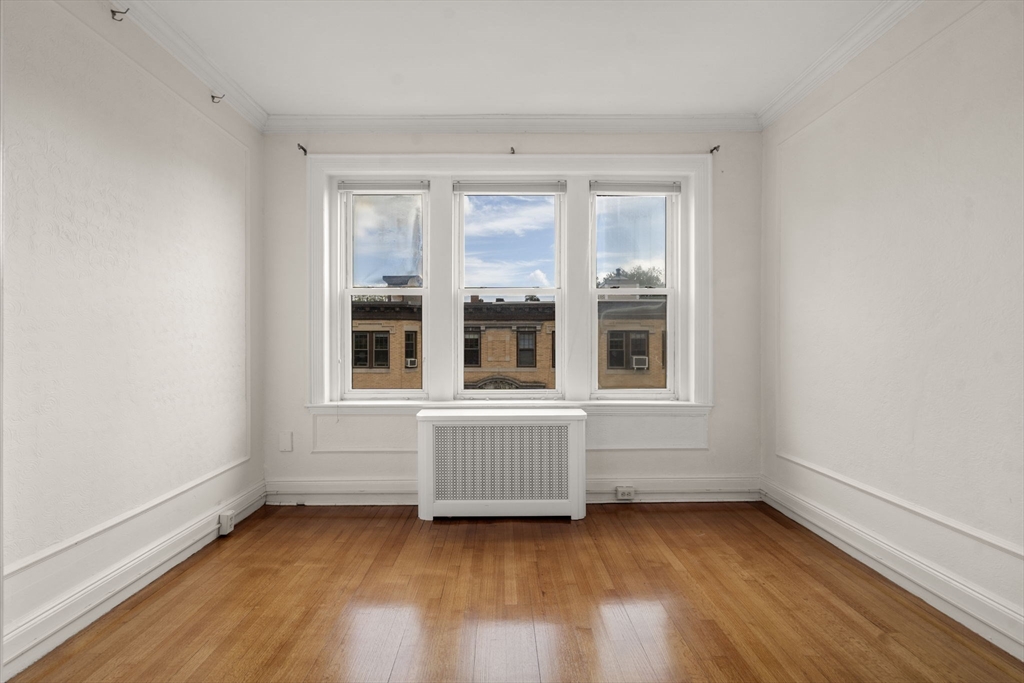 114 St Paul Street, Unit 5 Brookline, MA 02446 - Photo 5 of 22 a view of an empty room with wooden floor and a window