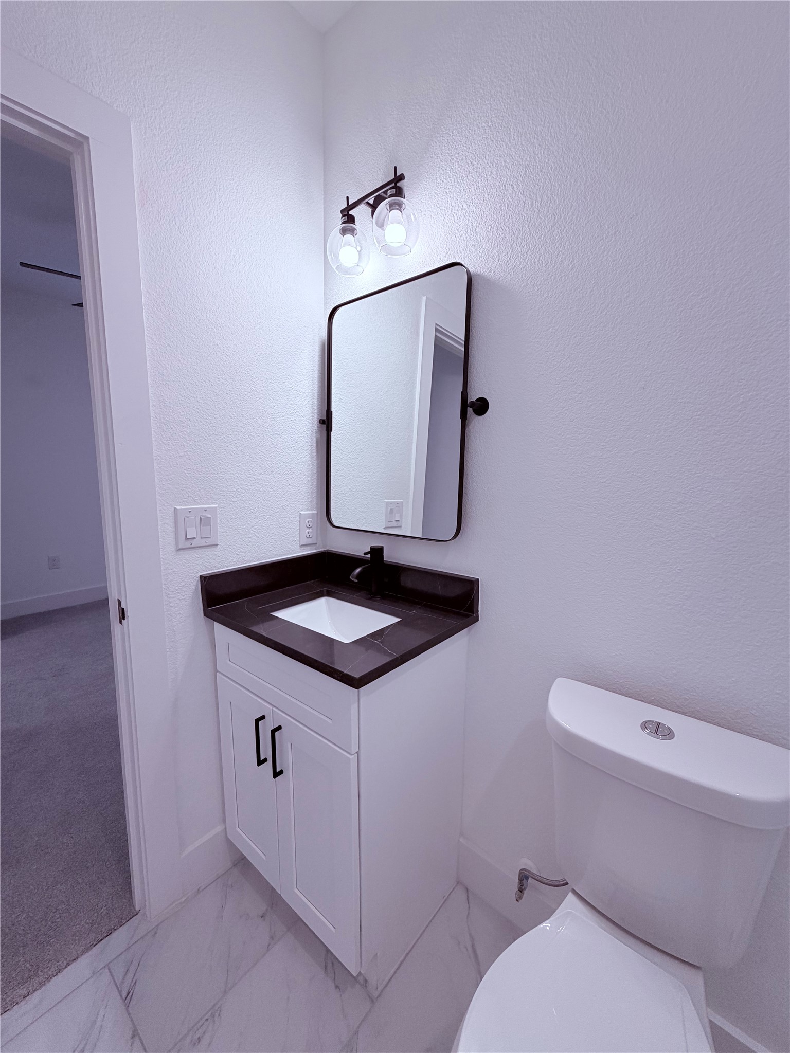 1417 Kramer Lane, Unit 7 Austin, TX 78758 - Photo 19 of 24 A well-appointed bathroom features a modern vanity with dark counters, a sleek mirror, and a contemporary light fixture.