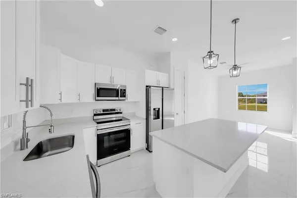 a large kitchen with stainless steel appliances kitchen island a large counter top and a sink