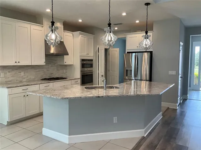 a kitchen with stainless steel appliances granite countertop a sink a stove and a refrigerator