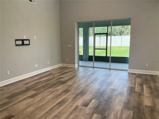 an empty room with wooden floor and balcony