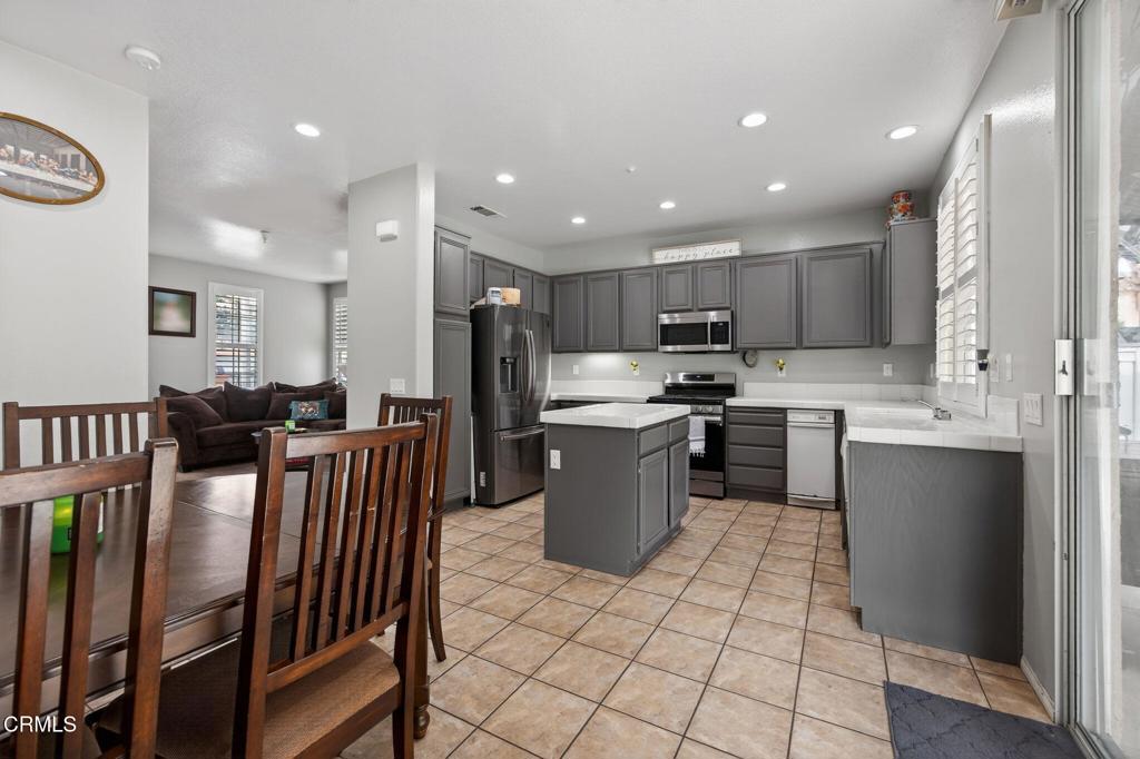 816 Noontide Way Oxnard, CA 93035 - Photo 11 of 41 a kitchen with stainless steel appliances kitchen island granite countertop a refrigerator a stove a sink a dining table and chairs