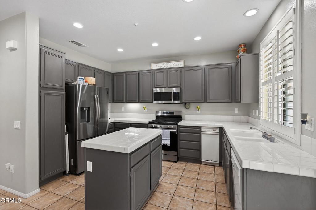 816 Noontide Way Oxnard, CA 93035 - Photo 14 of 41 a kitchen with a refrigerator a sink a stove top oven and cabinets
