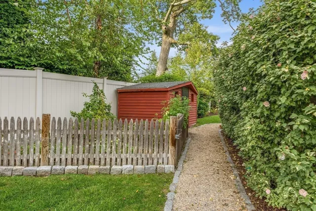 a side view of a house with a small yard and wooden fence