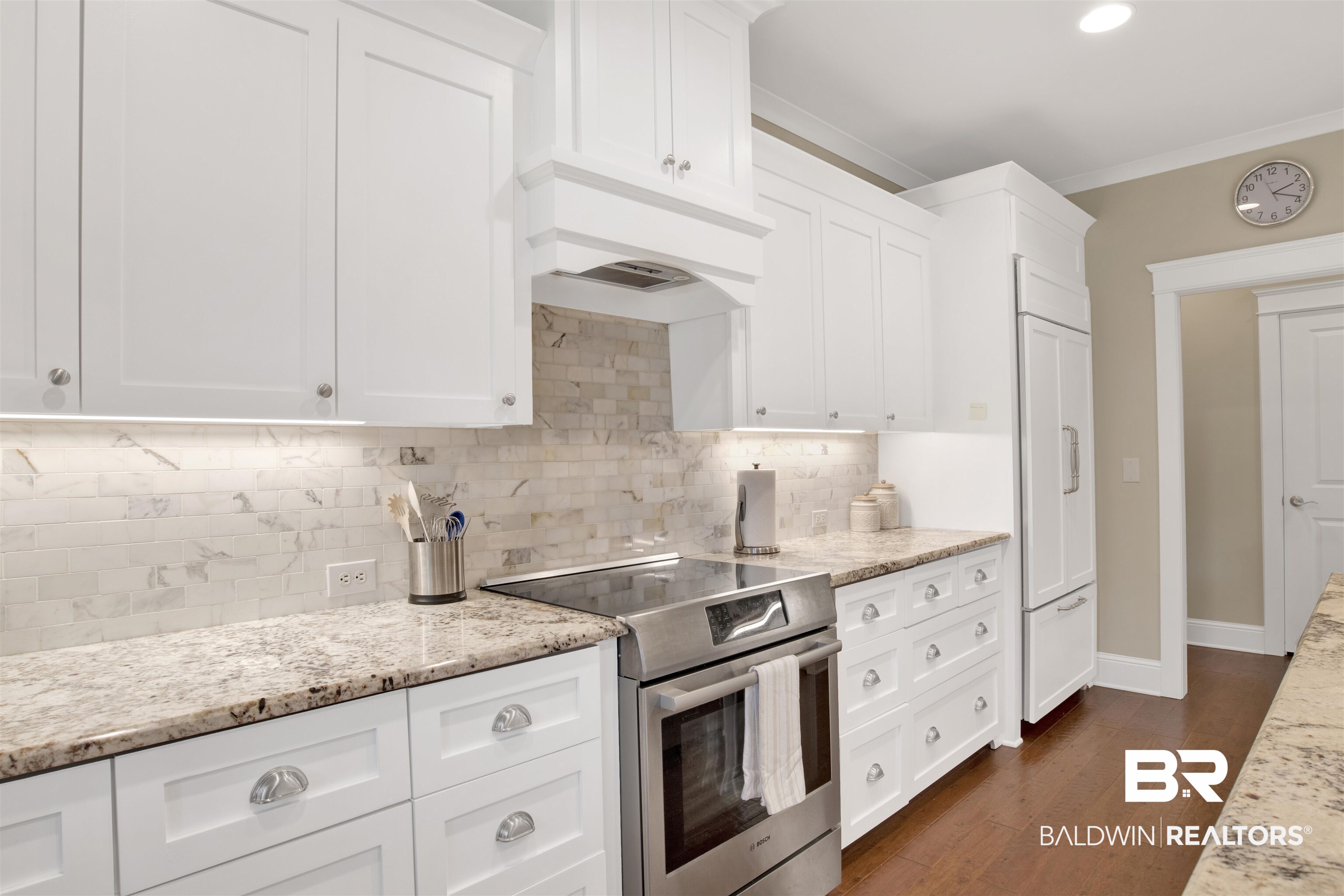 131 Sedgefield Avenue Fairhope, AL 36532 - Photo 17 of 50 Kitchen featuring induction cooktop, tasteful backsplash, white cabinetry, dark wood-type flooring, and ornamental molding