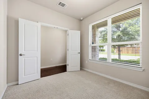 a view of an empty room with wooden floor and a ceiling fan