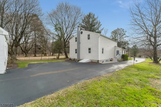 a view of a white house with a yard and large tree