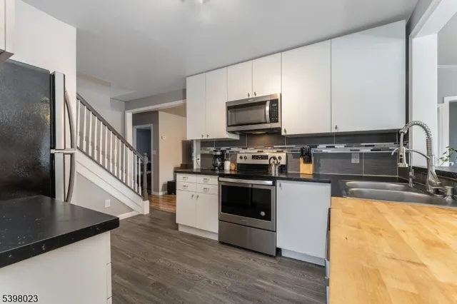 a kitchen with granite countertop a stove a sink and a microwave