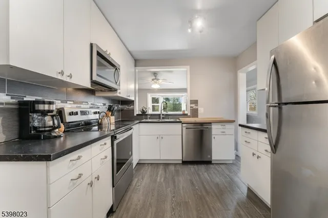 a kitchen with granite countertop a refrigerator stove top oven and sink