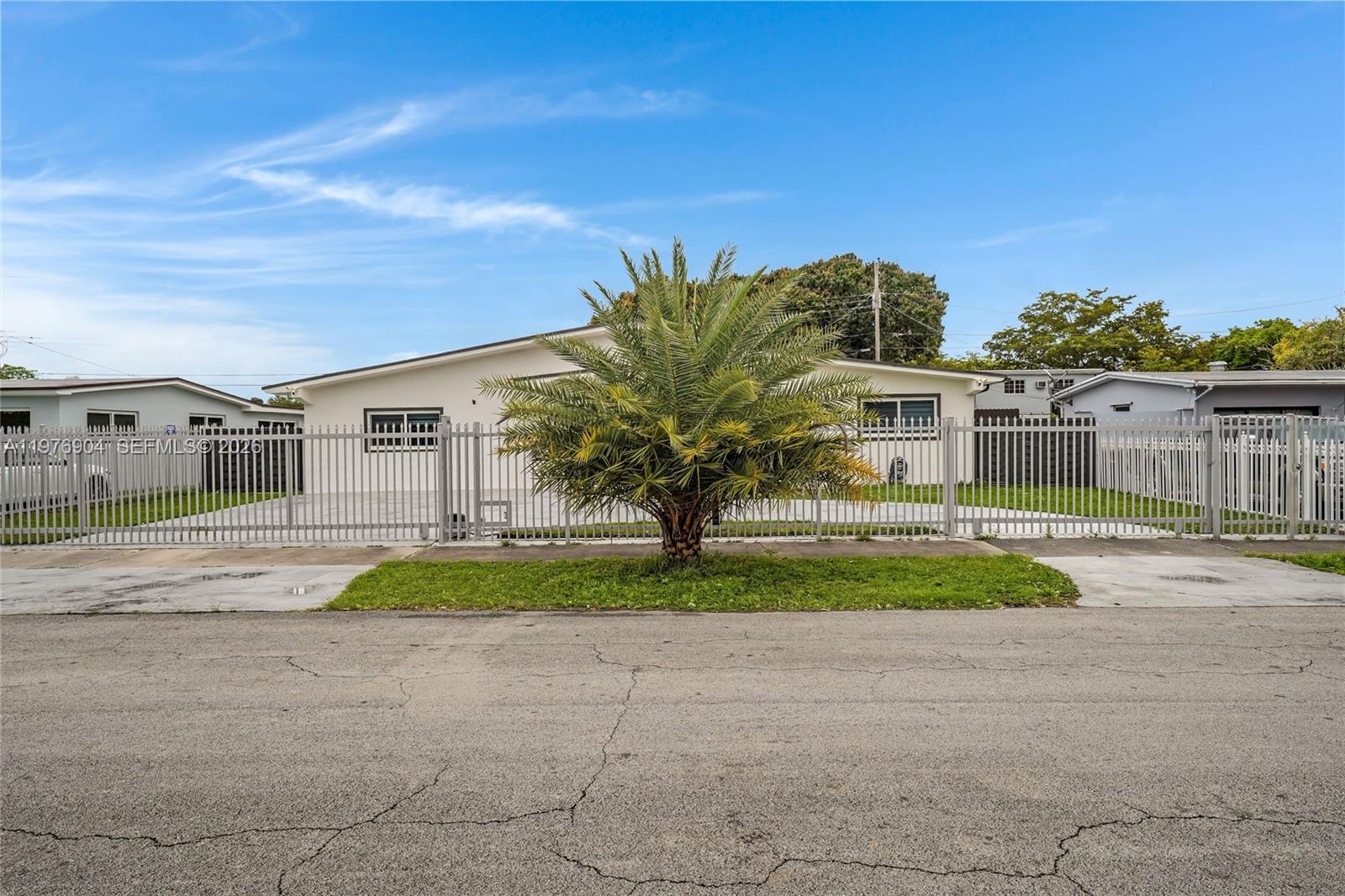 5635 West 13th Court Hialeah, FL 33012 - Photo 40 of 47 a view of a house with a yard and table and chairs under an umbrella