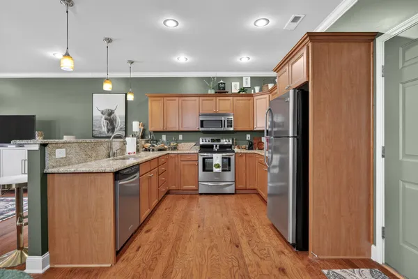 a kitchen with stainless steel appliances granite countertop a refrigerator a sink dishwasher a stove with wooden floor