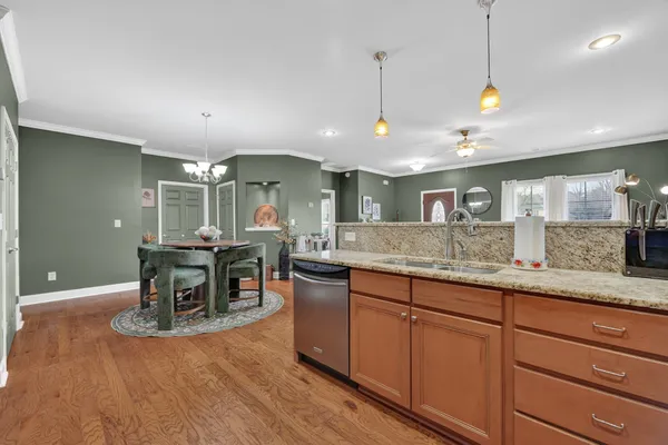 a kitchen with stainless steel appliances granite countertop dining table chairs and wooden floor