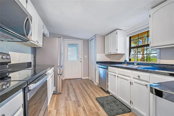 a kitchen with granite countertop a sink cabinets stainless steel appliances and a window