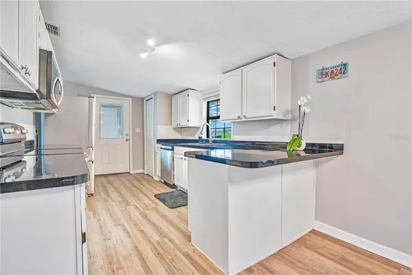 a kitchen with kitchen island granite countertop a sink cabinets and stainless steel appliances