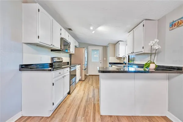 a kitchen with stainless steel appliances granite countertop a stove a sink and white cabinets