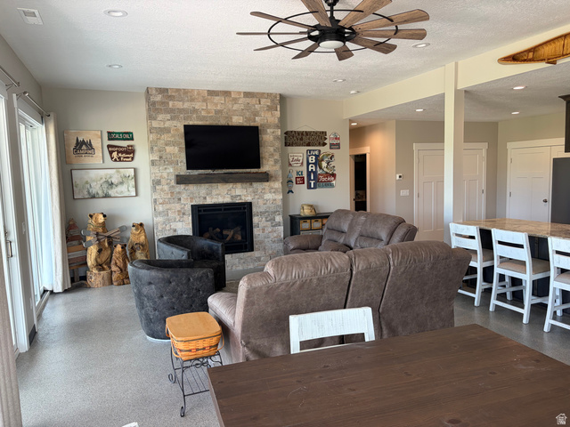 1325 South Round Road East Laketown, UT 84038 - Photo 25 of 40 Living area featuring a floor-to-ceiling stacked stone fireplace with a wood mantle, a ceiling fan, recessed lighting, and direct patio access