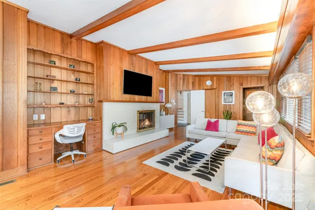 a work room with furniture a rug and a flat screen tv