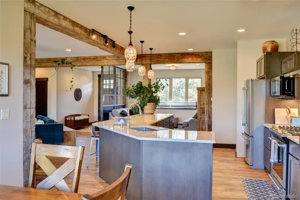 a dining hall with stainless steel appliances kitchen island granite countertop a table and chairs in it