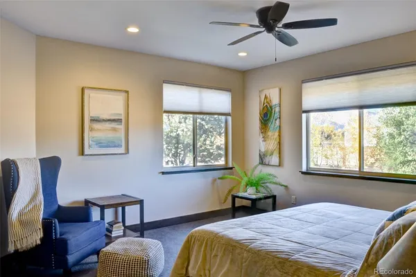 a bedroom with a bed table closet and two windows