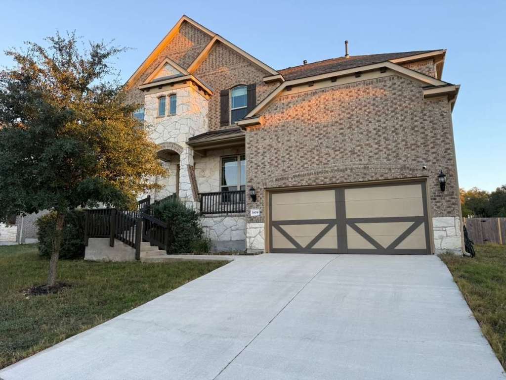 French country inspired facade with stone siding, concrete driveway, and a garage