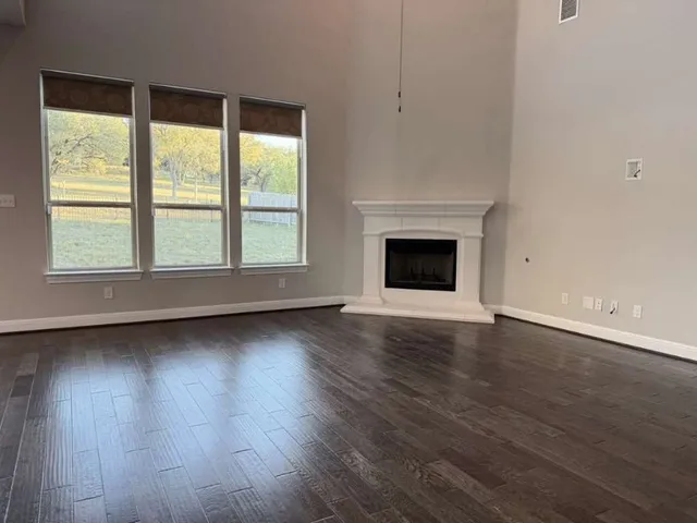 an empty room with wooden floor fireplace and windows