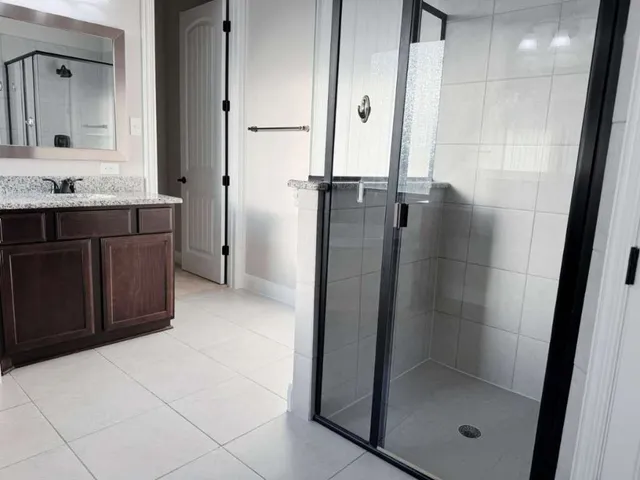 a bathroom with a granite countertop sink a mirror and shower