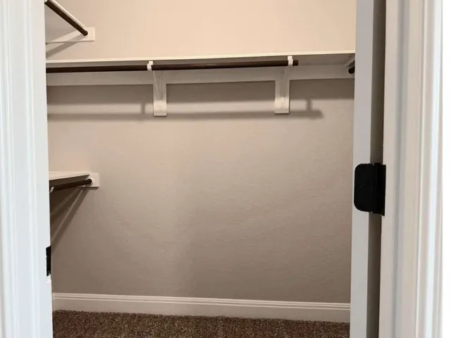 an empty room with a chandelier fan and windows