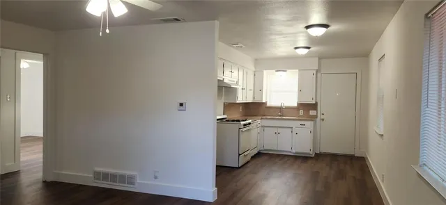 an empty room with wooden floor closet and windows