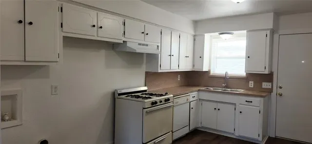 a kitchen with granite countertop a sink a stove and cabinets